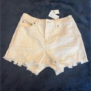 cream colored high waisted denim shorts with slight distressing at the bottom.